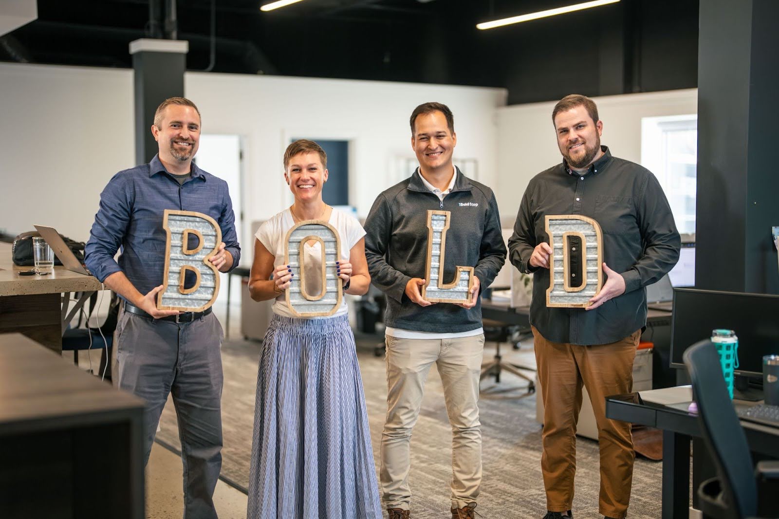 Team members hold letters that spell "Bold."