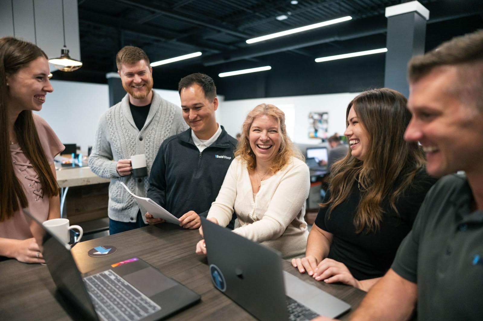 A happy fractional marketing team works together around a table.